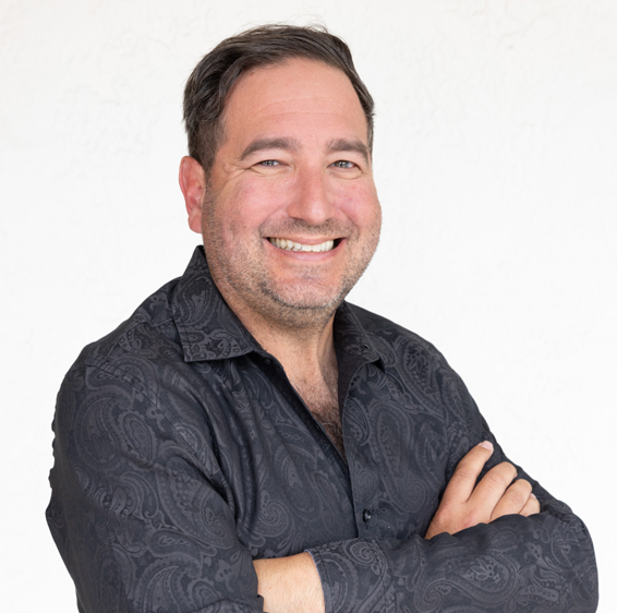 Professional headshot of male orthodontist smiling with arms crossed against white background.