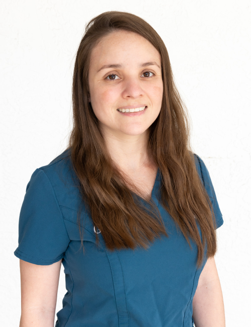 Young woman in blue scrubs smiling at camera, professional healthcare portrait.
