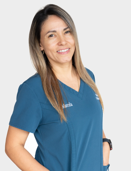 Female orthodontic professional in blue scrubs smiling at camera against white background.