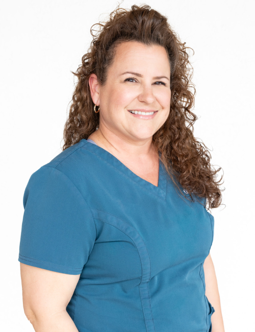 Woman in blue scrubs smiling at camera, professional orthodontics office portrait
